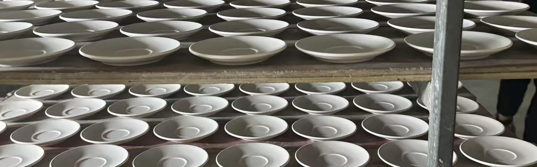 Stoneware plates on drying racks in a Vietnam ceramic factory