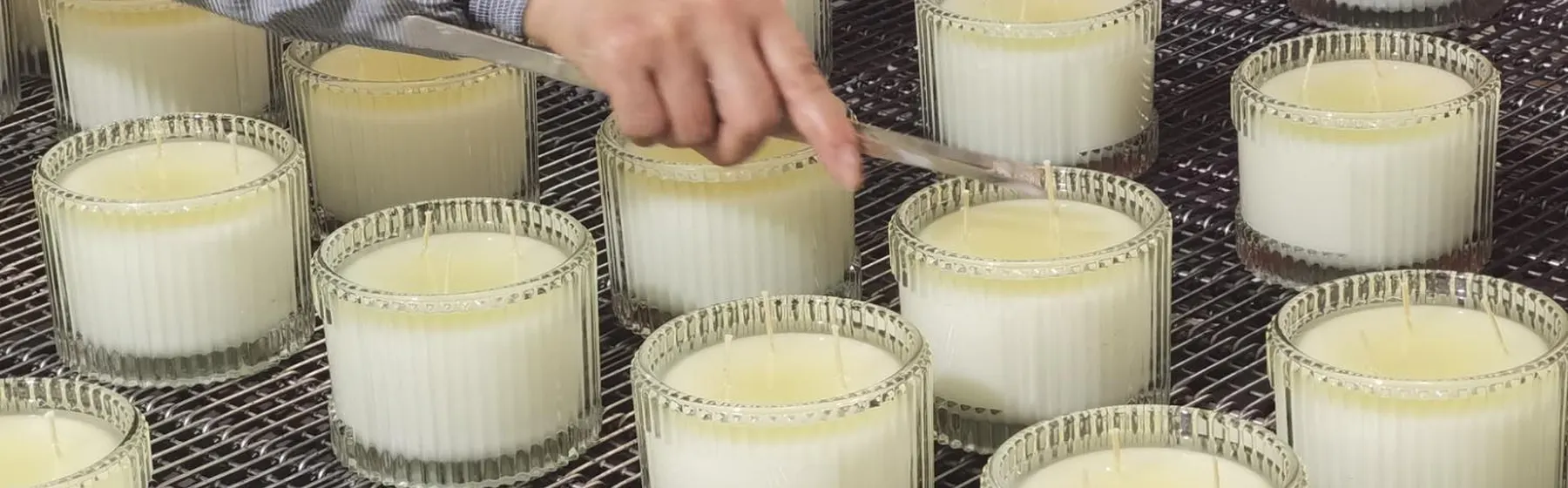 Hand finishing candles in ribbed glass jars