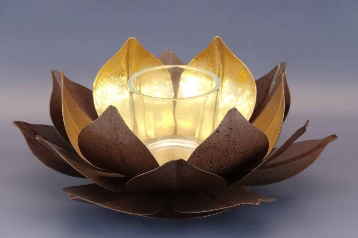 Lotus tealight holder with gold-leaf petals glowing around a glass cup
