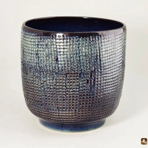 Textured ceramic vessel with deep blue reactive glaze