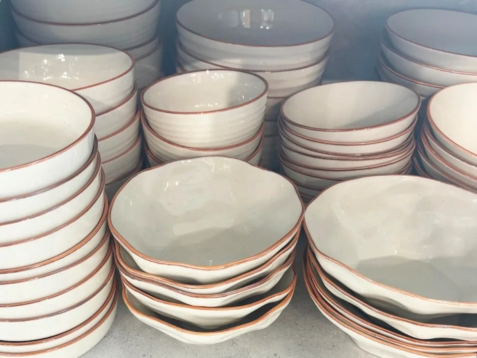 Stacks of speckled white bowls with a brown rim glaze