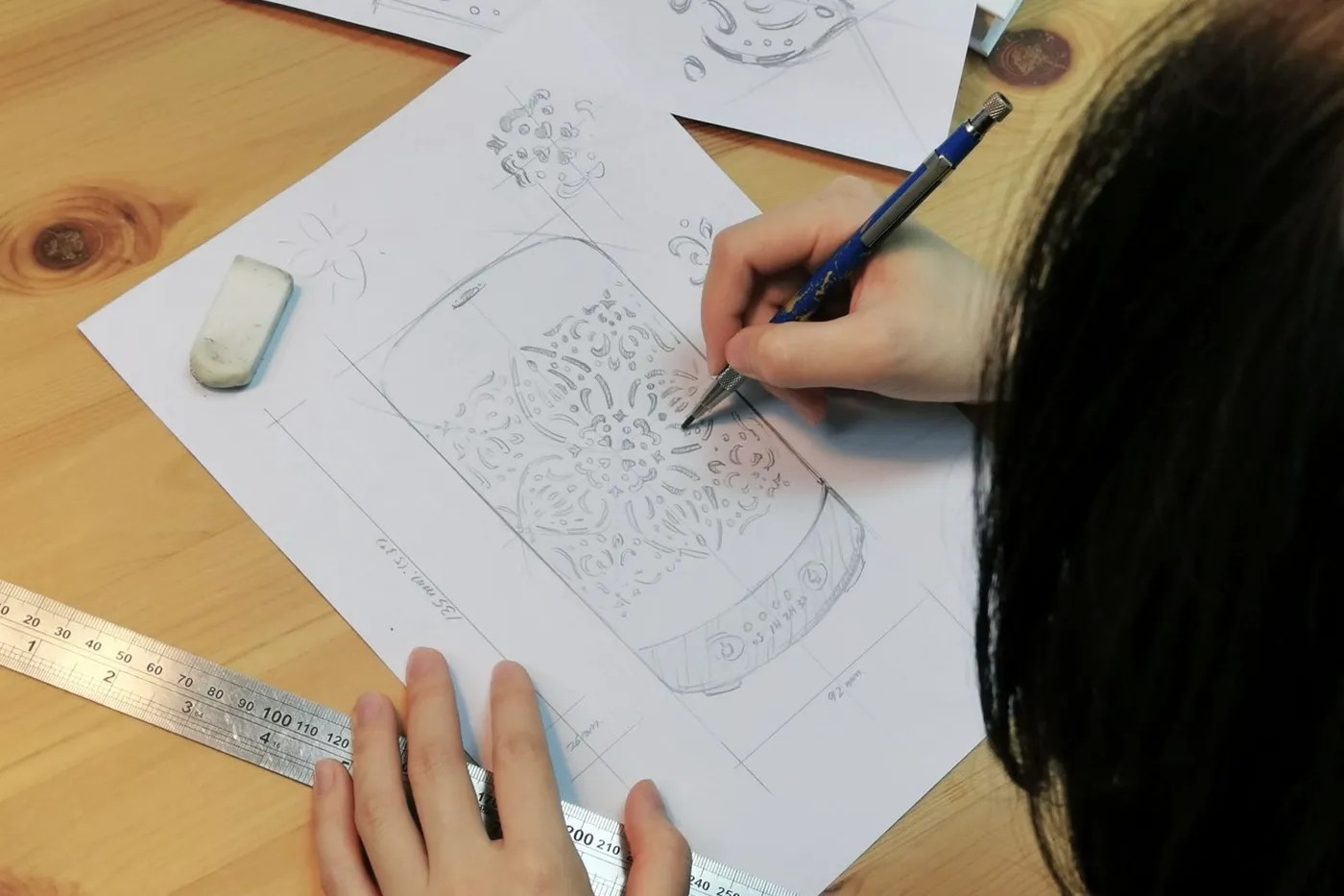 A designer sketching a carved product design with calipers and a ruler
