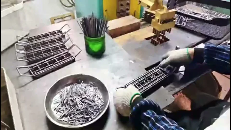 Hands in work gloves assembling wire parts on a jig